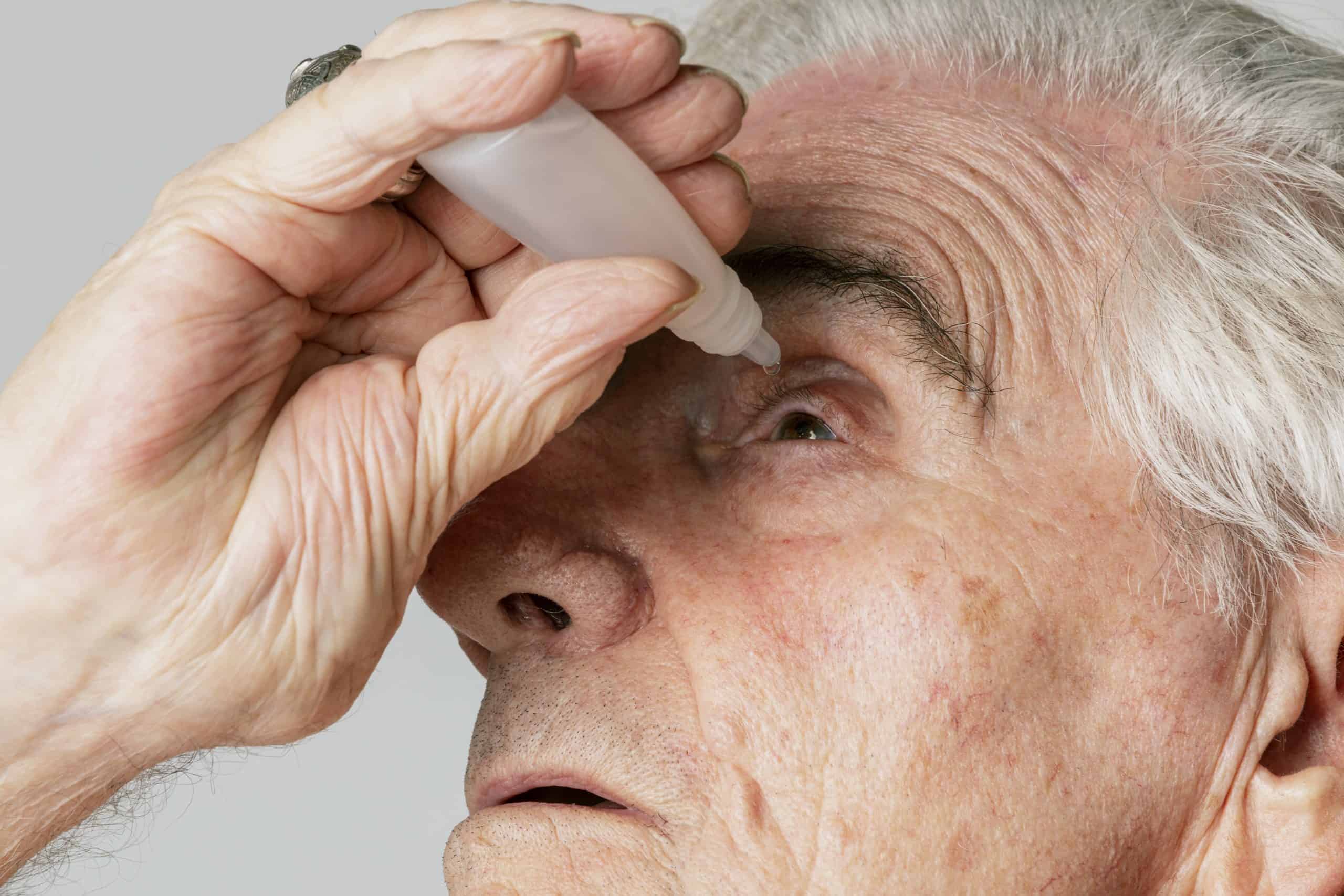 Closeup senior man applying eye drops